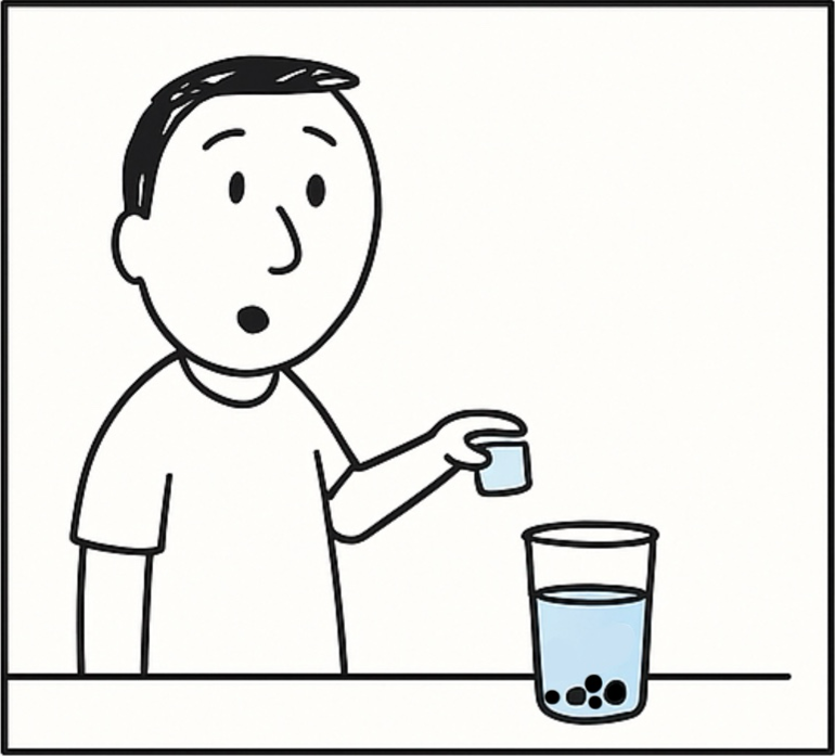 An instructor holds a small container above a cup of water with black pebbles sunken at the bottom.