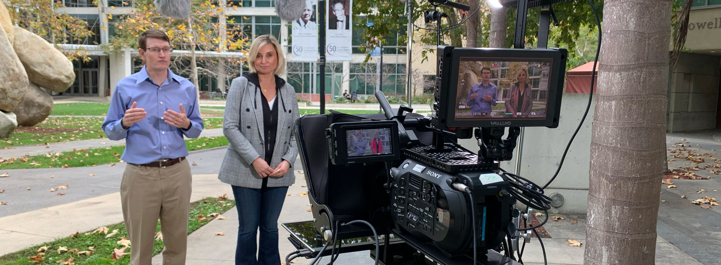Photo of two people standing in front of a video camera on the UCSD campus