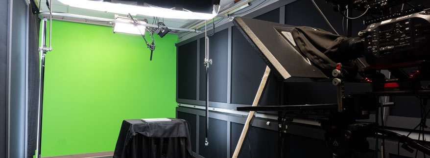Photo of a video studio with a green wall in the background and camera in the foreground